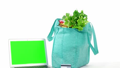 verduras frescas en una bolsa de compras con portátil