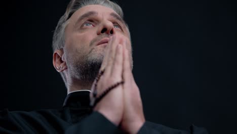 christian priest in cassock praying in church, rosary, faith and belief