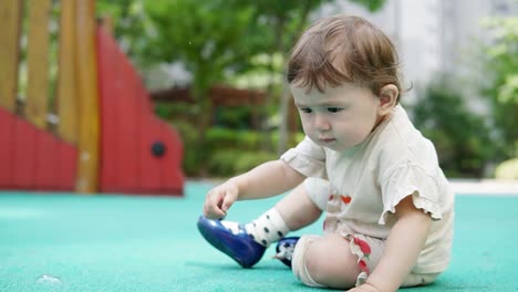 While-mom-or-dad-blows-bubbles,-baby-is-interested-in-picking-up-rocks-on-the-playground