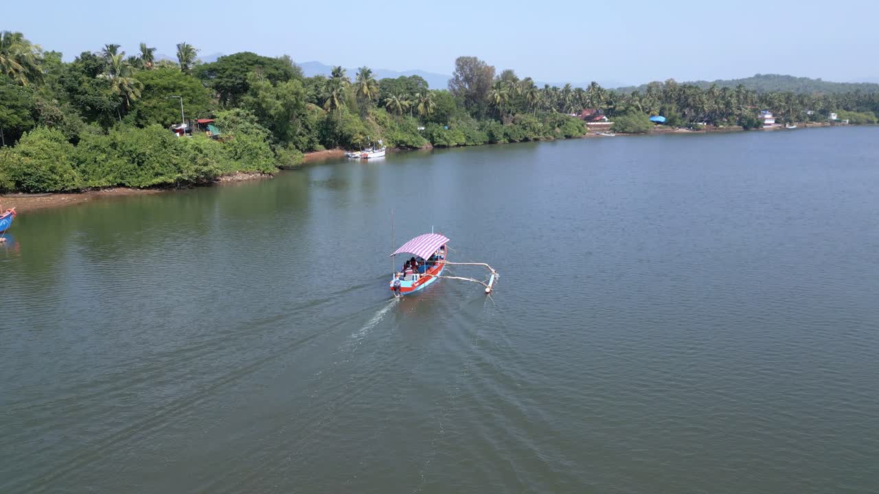 Aerial view of scenic boat trip from Patnem Beach along the serene Talpona River in Goa. Surrounded by lush trees, calm waters, and distant mountains on a sunny day