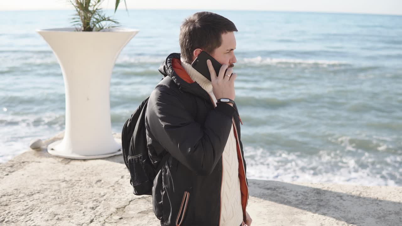 해변에서 전화로 얘기하는 남자