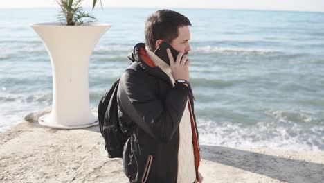 un hombre en una playa hablando por teléfono.