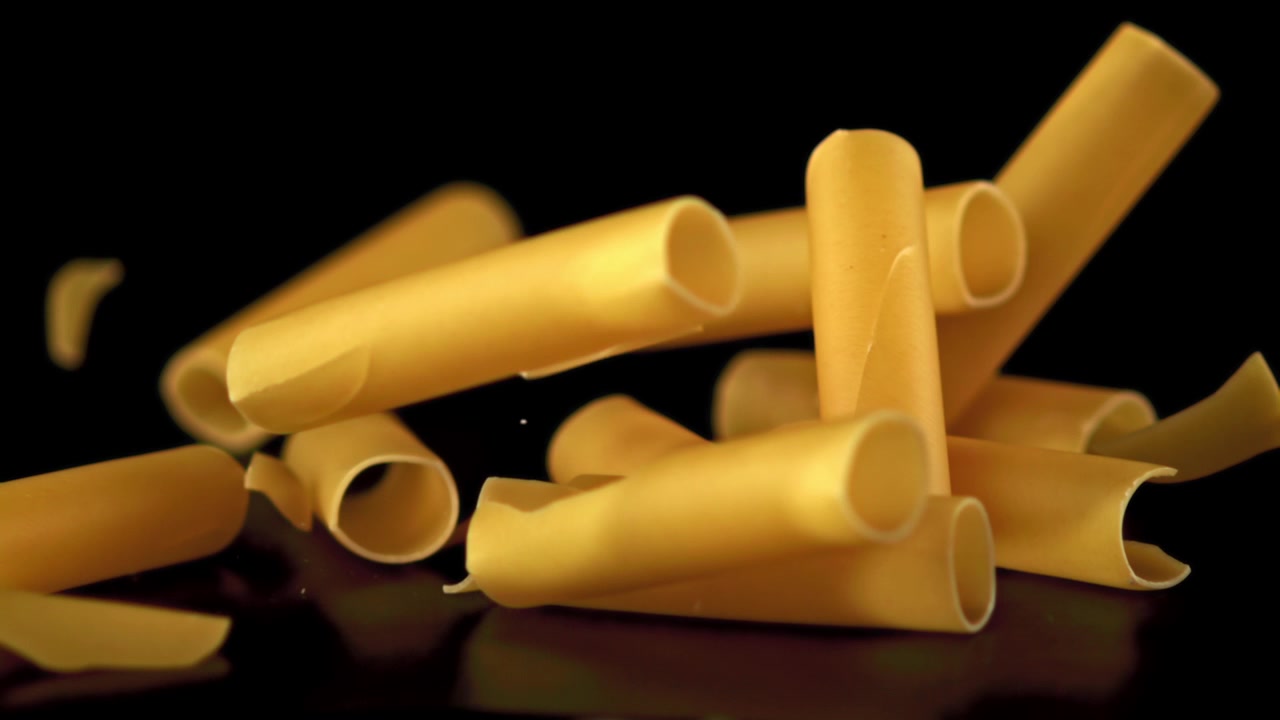 Cannelloni crudi che cadono su sfondo nero al rallentatore