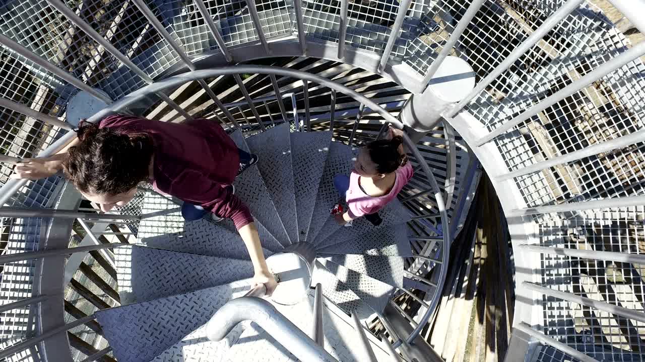 Due ragazze felici salgono le scale su una scala a chiocciola tortuosa in cima alla piattaforma panoramica.