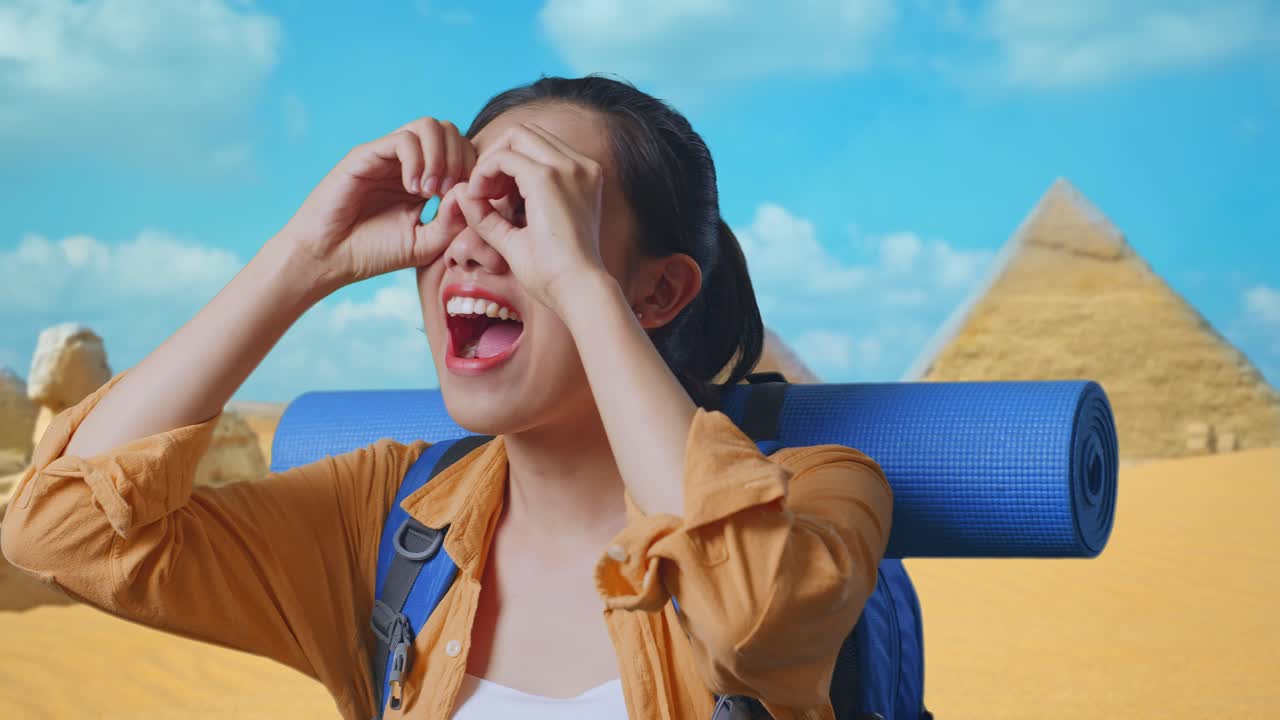 Close Up Of Asian Female Hiker With Mountaineering Backpack Making Binoculars Gesture Looking At Something Then Saying Wow While Traveling In Pyramid Of Giza