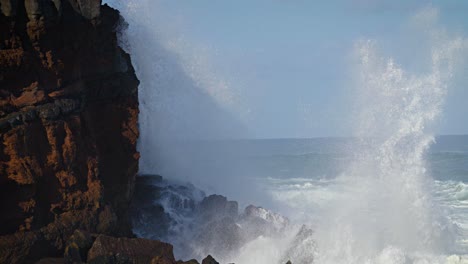 large waves roll into the coast of hawaii in slow motion and break along a craggy coast 2