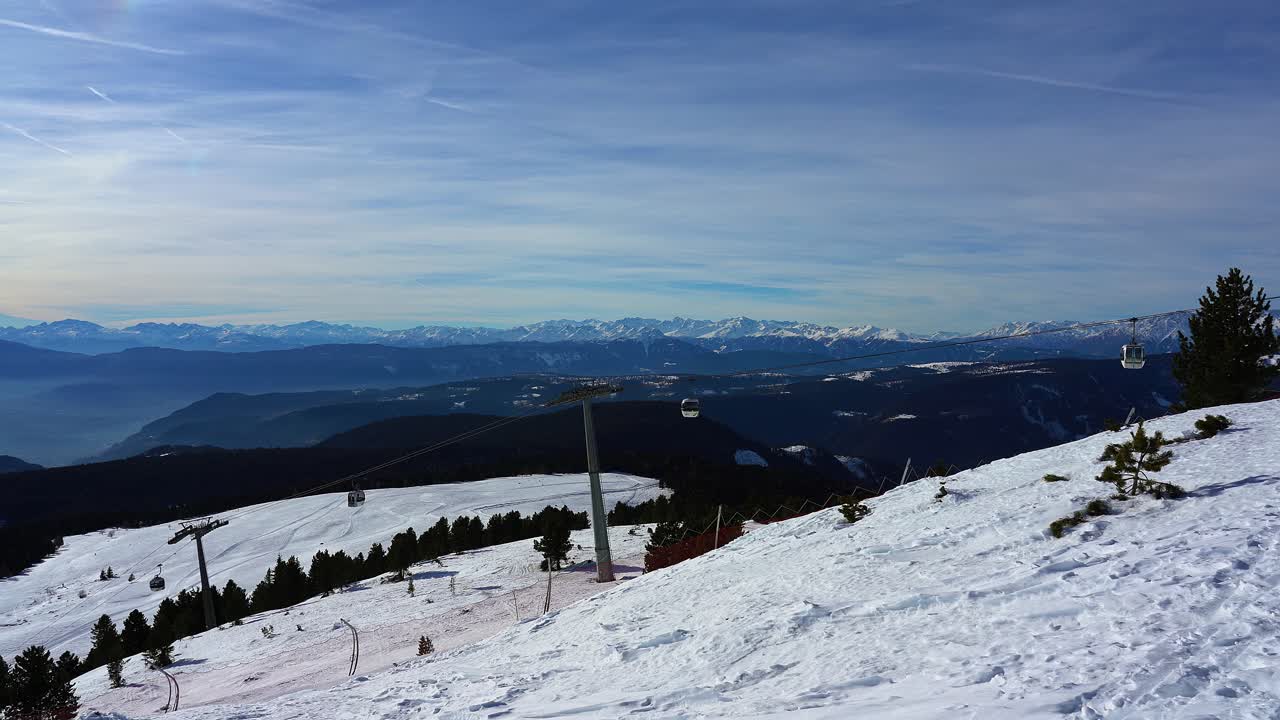눈 덮인 산 정상으로 오르는 케이블카를 보여주는 스키 리조트의 패닝 뷰