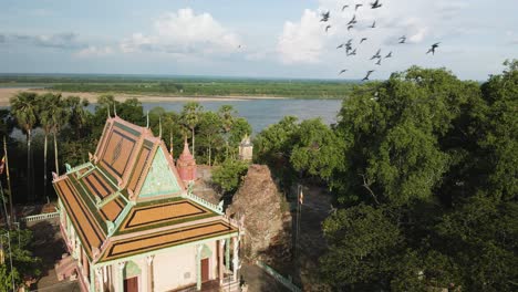 Hermosa-Pagoda-Con-Pájaros-En-Cámara-Lenta-Volando,-Al-Lado-Del-Pintoresco-Río-Mekong