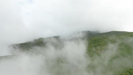 Clouds-forming-on-highland-plateau-with-lush-green-vegetation,-aerial