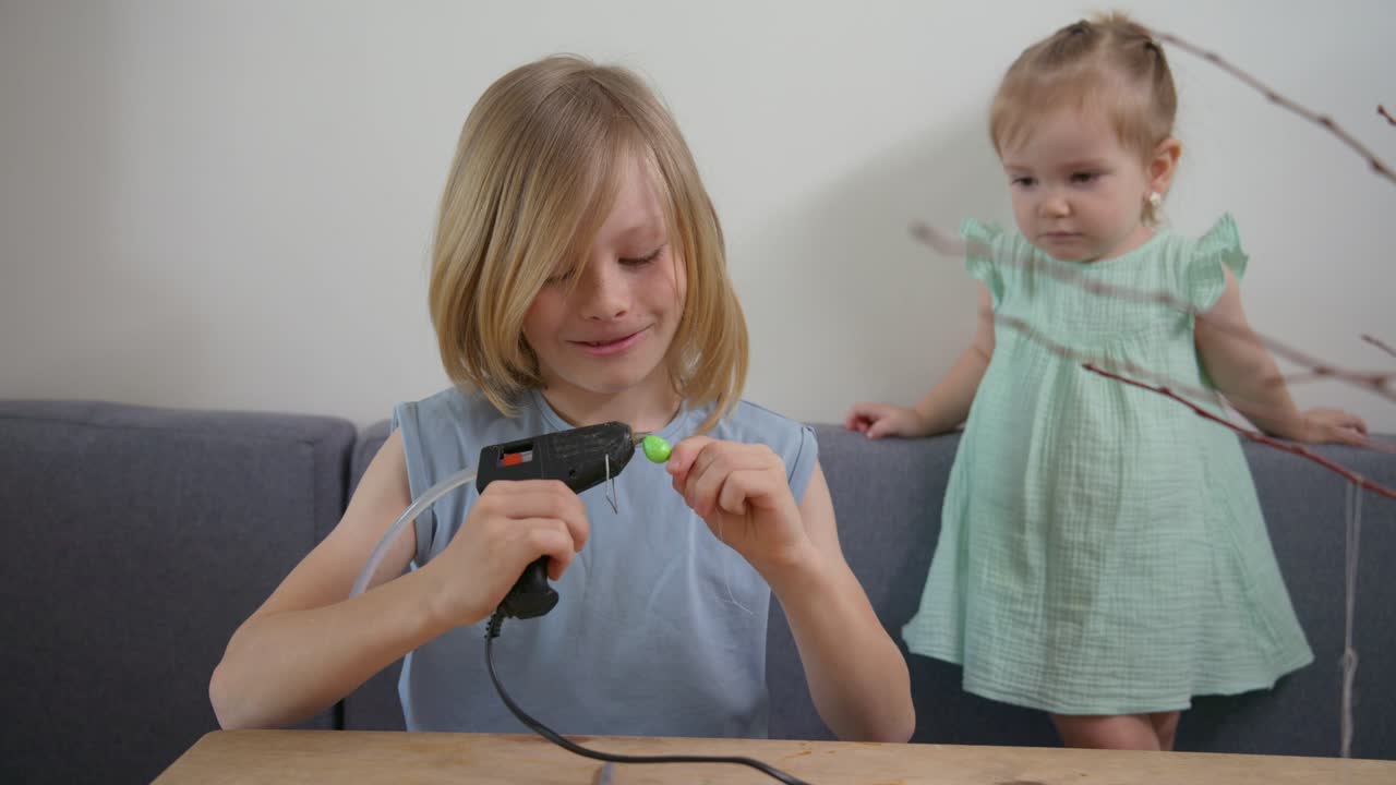 Bambino che usa una pistola per colla a caldo per un progetto creativo con la sorellina.