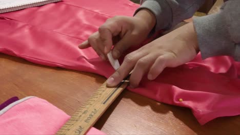 latin seamstress marking a dress with a white chalk an a curve ruler