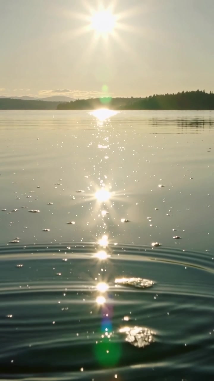 Vertikal video: Reaktion på sten, der lander, solens genskær, der bølger over søen med linseglimt.