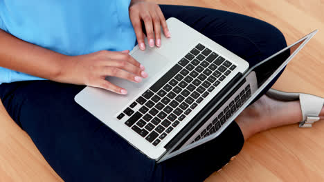 female executive using laptop while sitting on wooden floor 4k