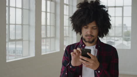 portrait of young mixed race man student using smartphone texting browsing online social media messaging on mobile phone technology in apartment