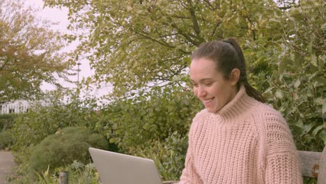 Mujer-Trabajando-En-Una-Computadora-Portátil-En-Un-Parque-Celebrando-Feliz