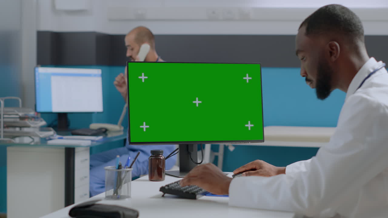 Doctors Working in Clinic with Green Screen Monitor