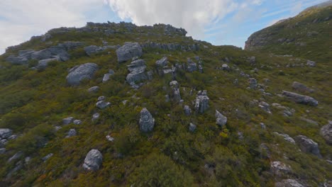 Long-aerial-shot-flying-over-the-spectacular-rocky-surface-of-Table-Mountain-in-Cape-Town,-South-Africa,-and-into-the-fog