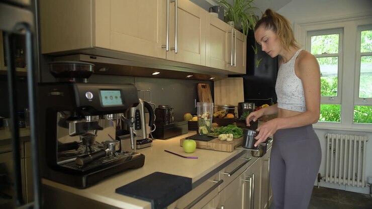 Giovane donna che inserisce gli ingredienti nel bicchiere del frullatore