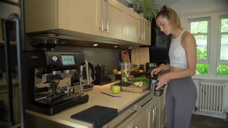 young woman placing ingredients into blender cup