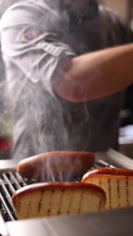 chef cocinando perritos calientes en la parrilla