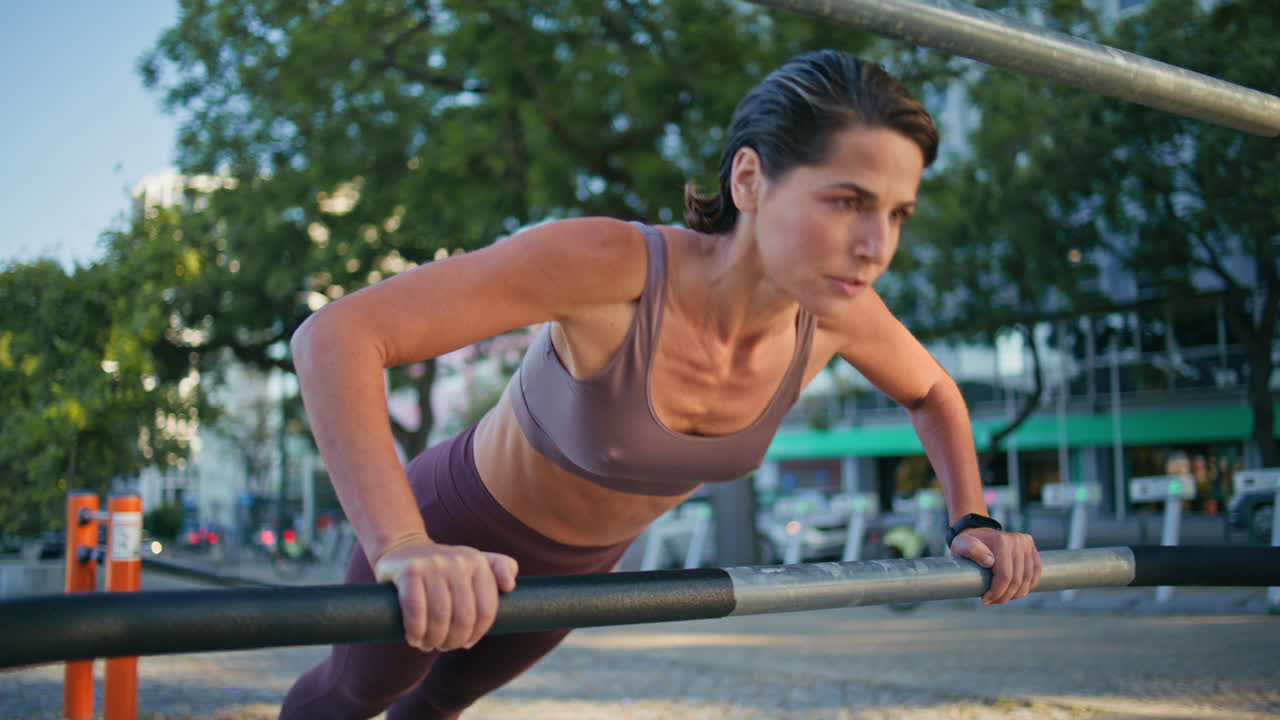 mujer atleta push ups ejercicios de fitness entrenamiento en la calle de cerca. dama usando bar