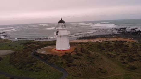 waipapa lighthouse aerial orbit shot at wild new zealand coast during cold cloudy morning