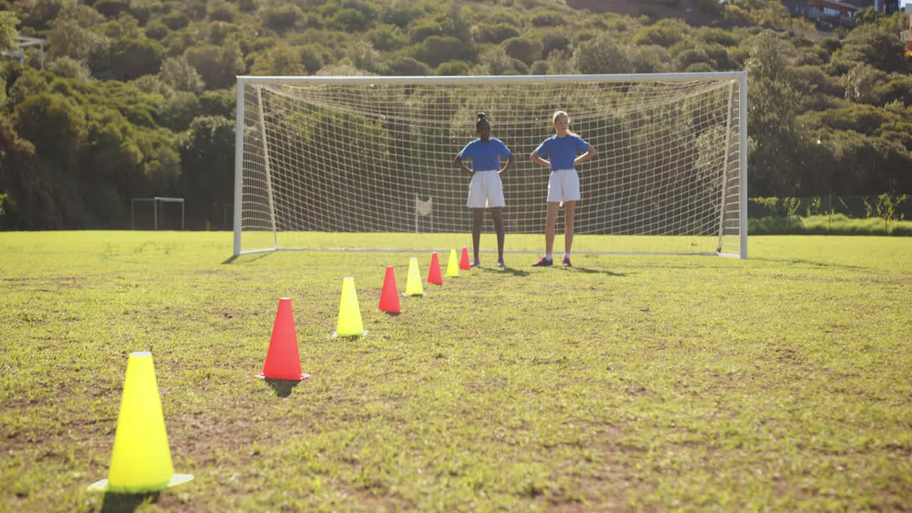 Playing soccer, girls practicing dribbling through cones on school field