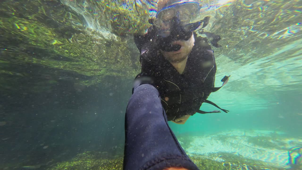 Over-Under water selfie: Man snorkels in clear river water current