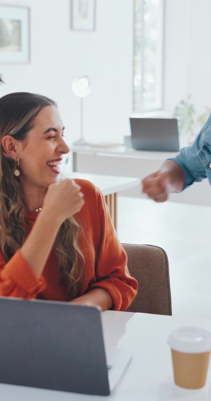 Donna d'affari entusiasta che festeggia un successo con una collega in un ufficio moderno