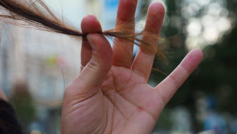 woman holds a strand of hair in her hand