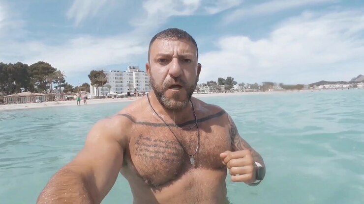 Mand optager sig selv, mens han bader på stranden