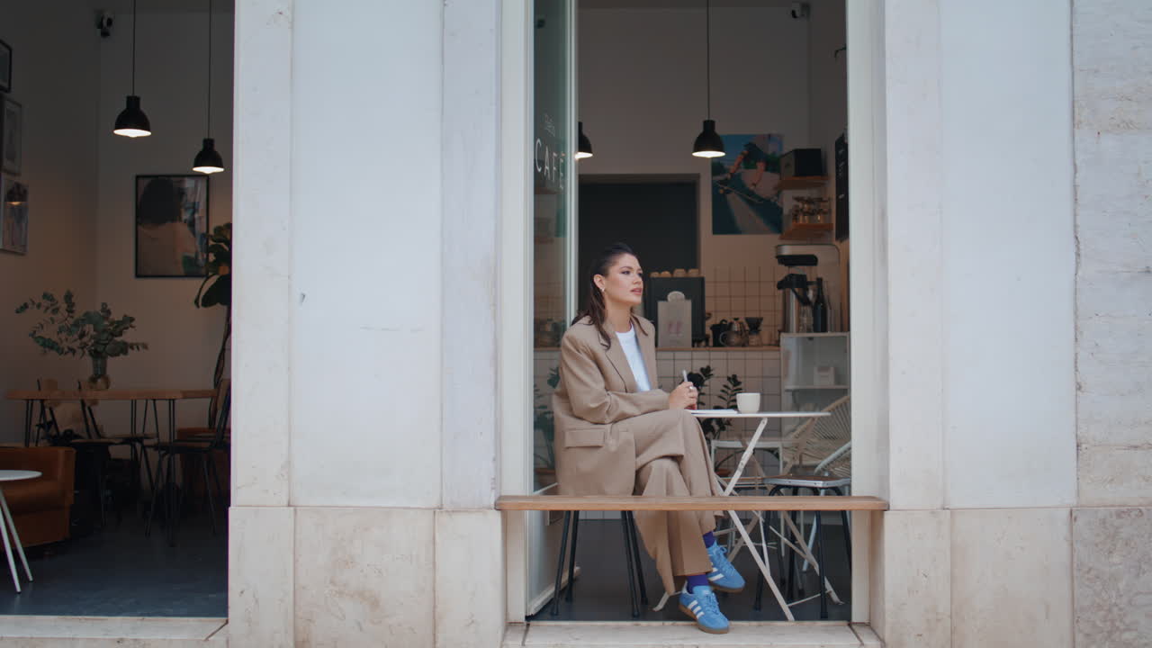 hermosa freelance descansando mesa de café mirando en la calle urbana. mujer elegante