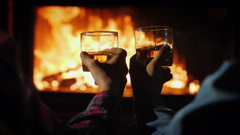 two men are drinking strong alcohol by the fireplace in the frame are visible hands with glasses aga