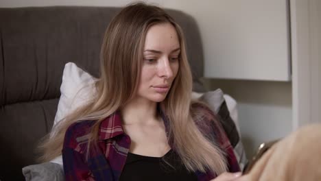 Blonde-Frau-Sitzt-Morgens-Im-Bett-Und-Surft-Mit-Dem-Smartphone-Im-Internet