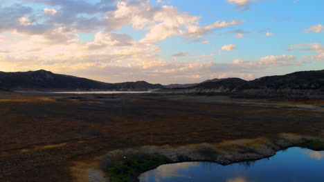 Pull-back-from-dry-lake-bed-to-low-water-levels-of-dried-up,-drought-stricken-Irvine-Lake-reservoir-in-Southern-California-with-aerial-drone-4k