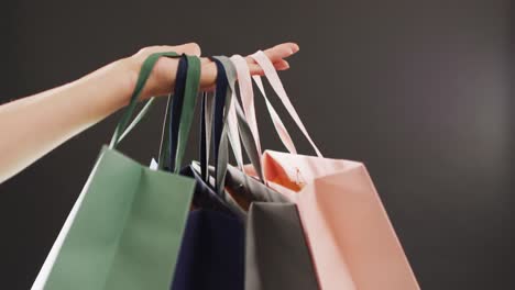 Woman's-hand-holding-gift-bags-on-black-background-with-copy-space