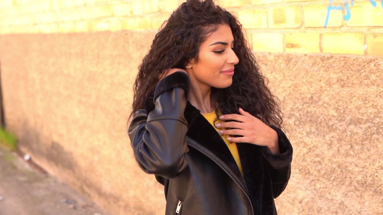 Giovane donna araba che cammina all'aperto muovendo i suoi capelli neri e ricci