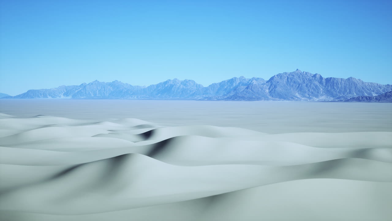 A vast desert landscape with white sand dunes and mountains in the distance under a clear blue sky