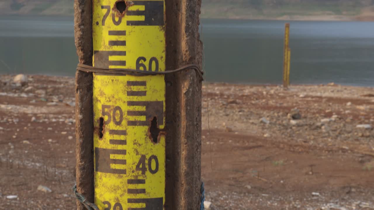 tiro inclinado de un viejo puesto de indicador de nivel de agua oxidado en el borde del agua con vista al lago, la cordillera y el cielo azul en un parque nacional