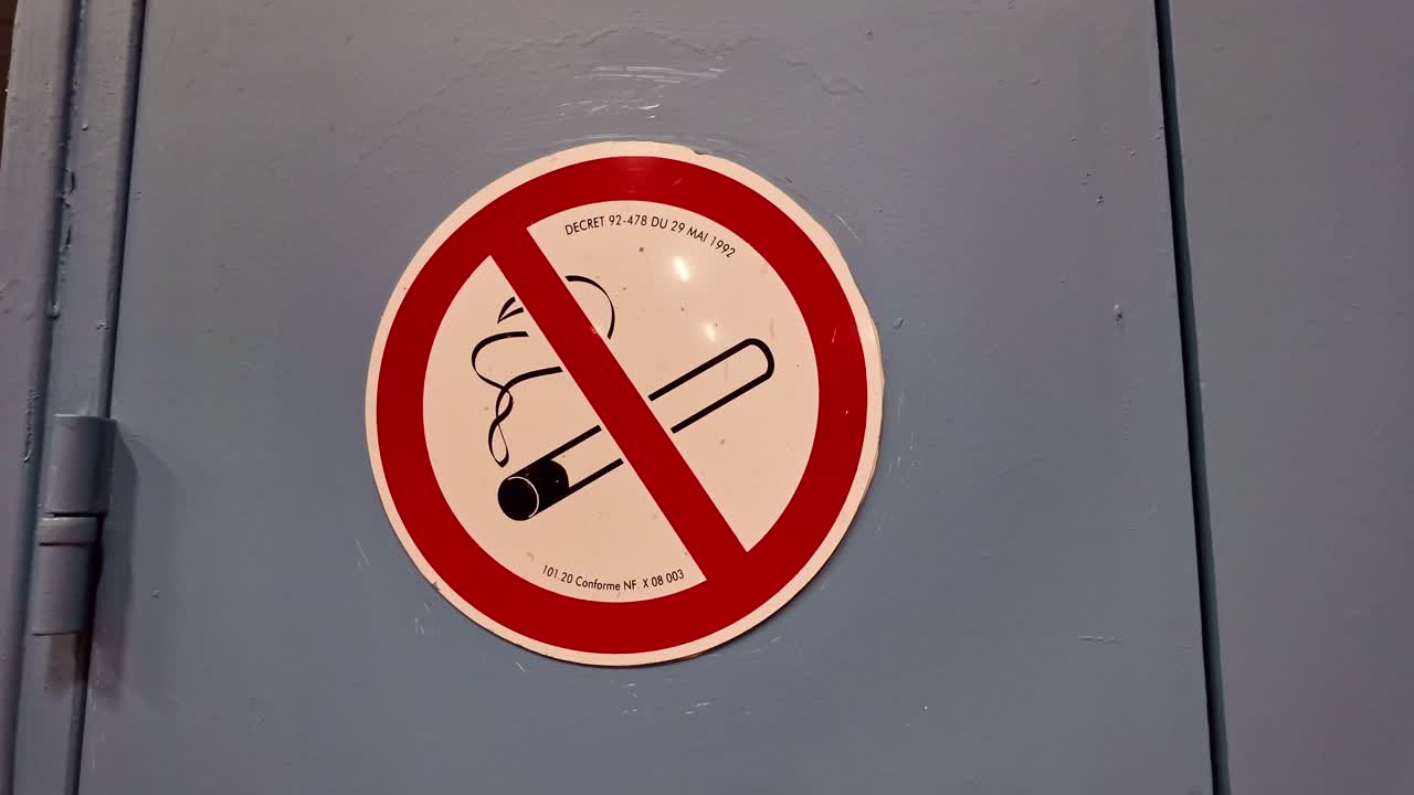 'No smoking' prohibition ban sign mounted on gray metal door as emergency warning