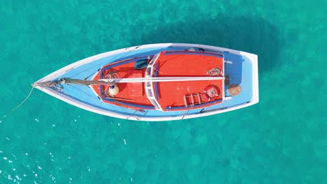 Der-Mast-Eines-Segelboots-Schwankt-Hin-Und-Her,-Während-Das-Verankerte-Boot-Im-Klaren-Wasser-Liegt