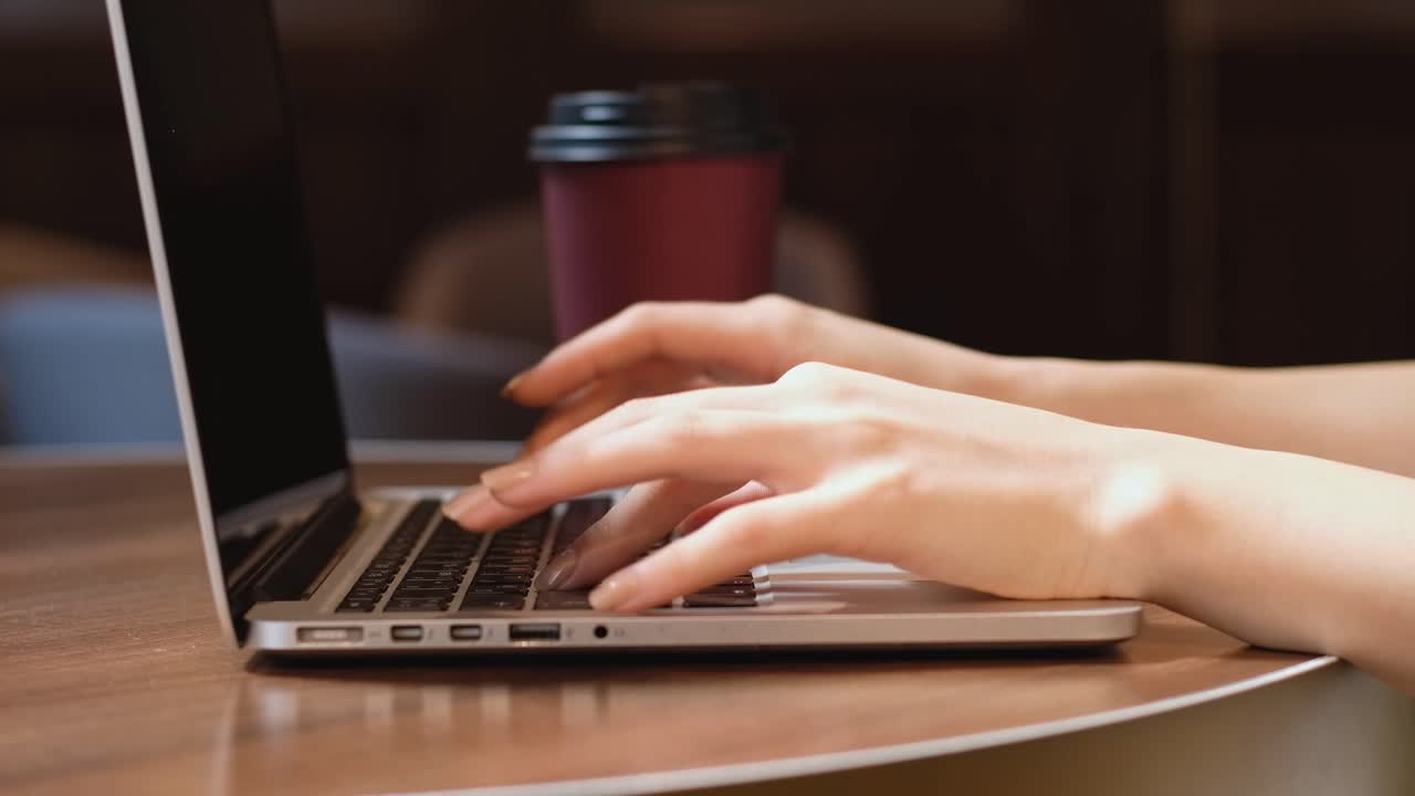 Young girl typing on laptop in a cafe