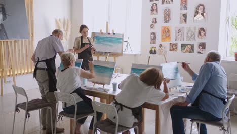 young woman teaches elderly students to draw pictures in courses for rehabilitation and development of retirees