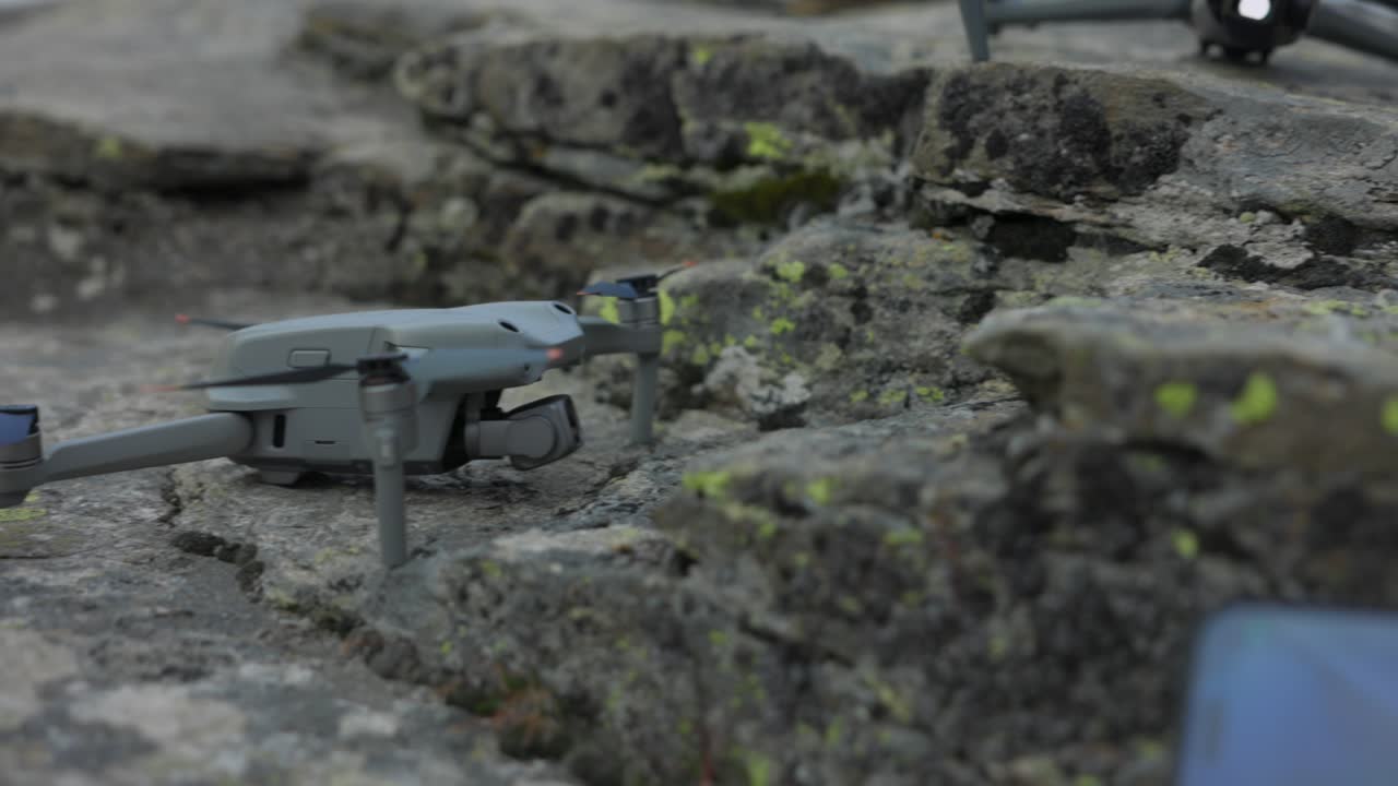 dji air 2s와 air 3은 하늘을 배경으로 바위 위에 놓은 현대적인 드론입니다.