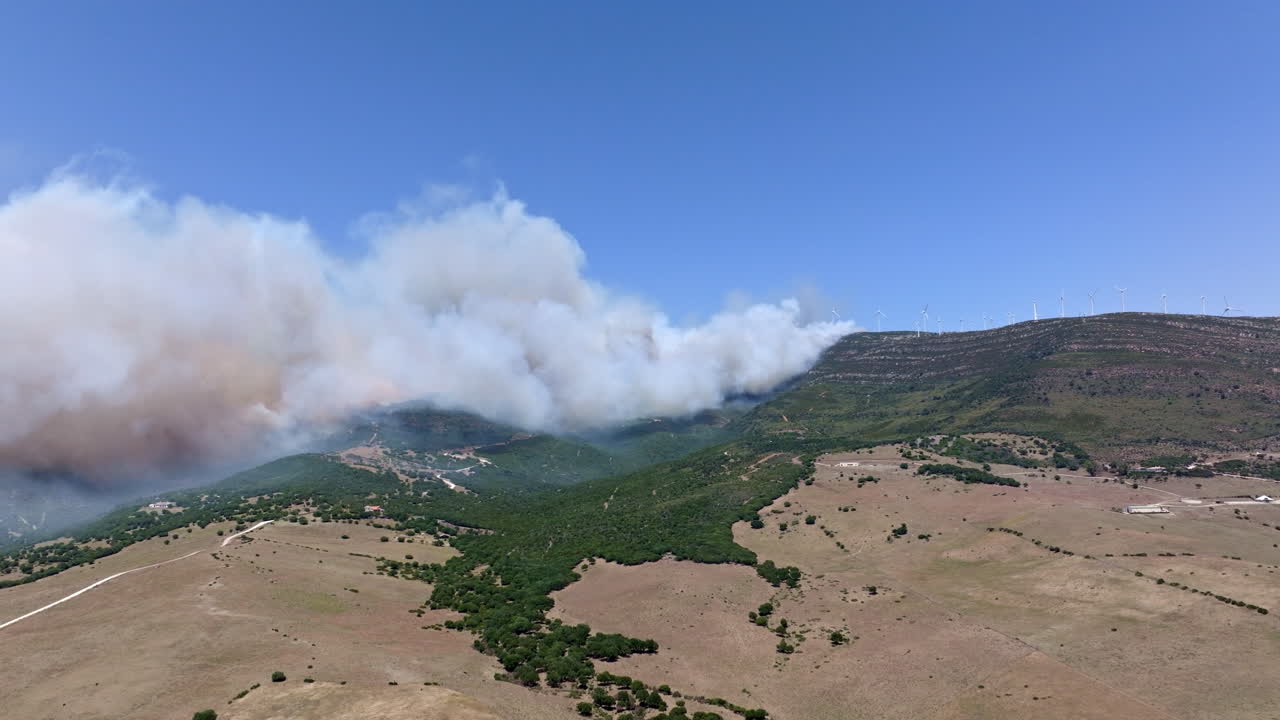 Wildfire engulfs the mountain peak of Valdevaqueros in Tarifa, Spain. Flames rage to the summit due to extreme heat and dryness, creating a dramatic and destructive scene.