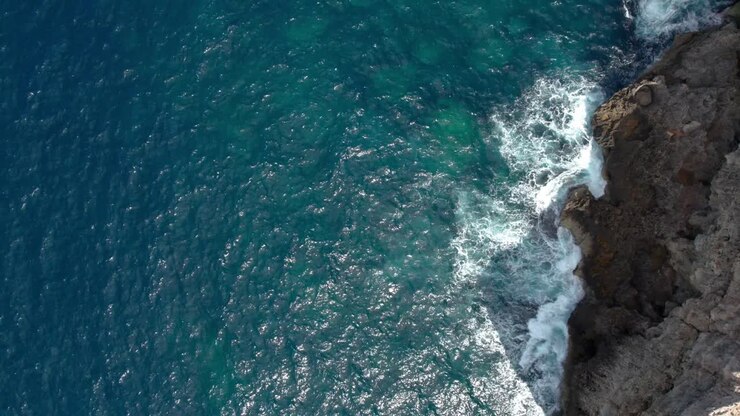 Vista dall'alto su un litorale roccioso a Malta, con onde che si infrangono e acqua cristallina turchese