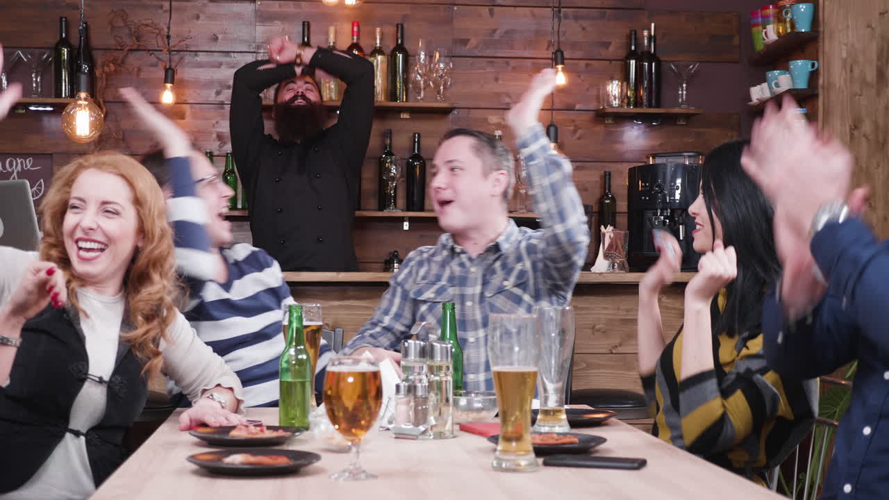 Entusiastisk gruppe fejrer på en bar