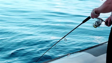 Man-reeling-in-the-line-of-a-fishing-rod-from-an-inflatable-boat