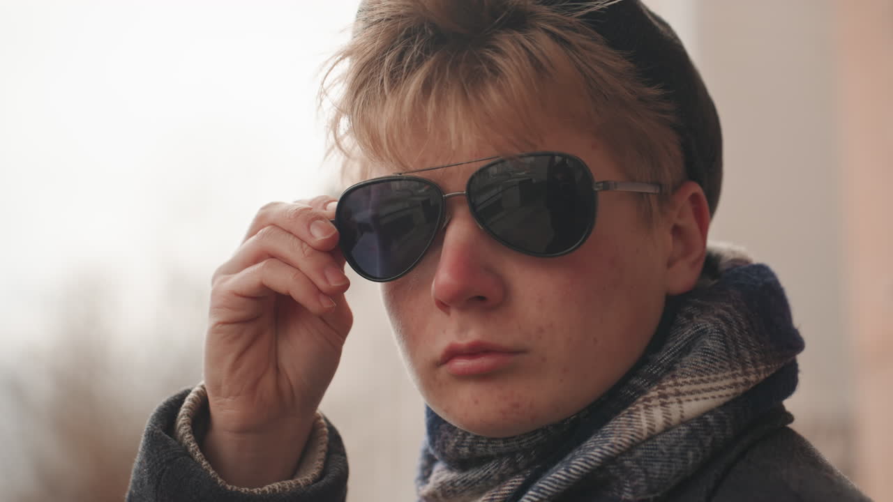 Chic street explorer with vintage style analyzes skyline scenery thoughtfully. Stylish individual with sunglasses gazes over city skyline capturing architectural details with artistic intent