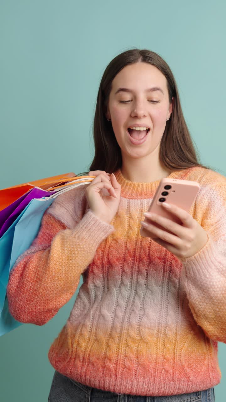 Happy woman enjoying shopping with colored bags and smartphone